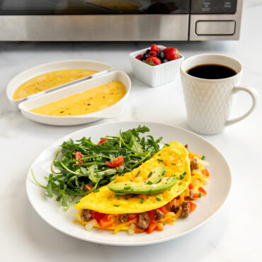 Nordic Ware omelet maker with golden cooked omelet on plate, fresh berries, and coffee cup on kitchen counter