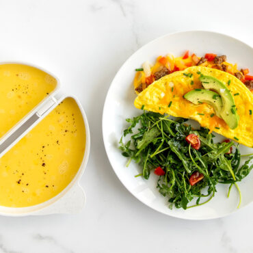 Nordic Ware omelet pan with cooked yellow omelet on plate and raw egg yolk in pan well