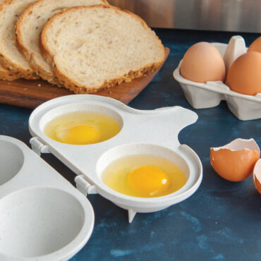 Two perfectly poached eggs with runny yolks in Nordic Ware aluminum egg poacher with black handles
