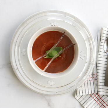 Nordic Ware clear microwave plate cover over white bowl of tomato soup with green herb garnish