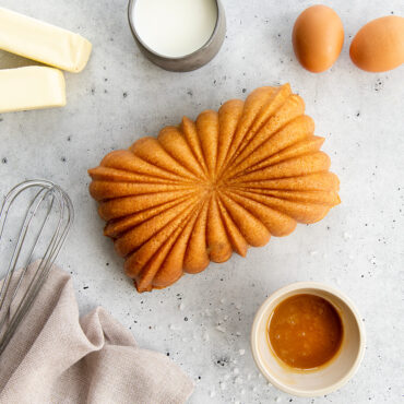 Golden salted caramel loaf cake baked in Nordic Ware fluted loaf pan with caramel drizzle and baking ingredients