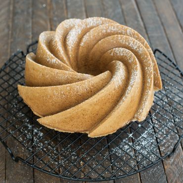 Golden bundt cake baked in Nordic Ware Heritage bundt pan, showing detailed swirled fluted design, dusted with powdered sugar