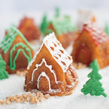 Golden brown gingerbread houses from Nordic Ware Cozy Village pan with white icing details and green decorative trees