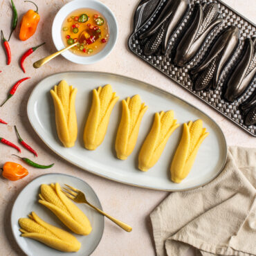 Plated Cornbread cakes surrounded by peppers and dish of honey