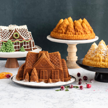 Two bundt cakes on stands: green-frosted Pine Forest cake with tree design and brown Gingerbread House cake with decorative details