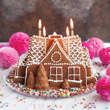 Decorated bundt cake baked in Nordic Ware Gingerbread House pan, showing house-shaped details with colorful icing
