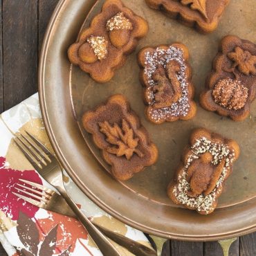 Six golden spice mini loaves with powdered sugar and chopped nuts, baked in Nordic Ware Harvest pan