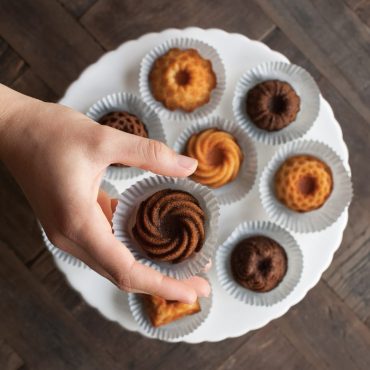 Hand selecting golden mini bundt cake from Nordic Ware aluminum Bundt Charms pan with 8 fluted cavities