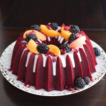 Red velvet bundt cake with white glaze and fresh berries in Nordic Ware Brilliance bundt pan
