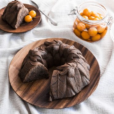 Chocolate bundt cake with detailed leaf pattern from Nordic Ware Harvest Leaves pan, dusted with powdered sugar, slice on side plate