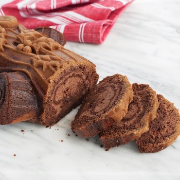 Nordic Ware aluminum yule log pan with baked chocolate cake shaped like tree branch, detailed bark texture