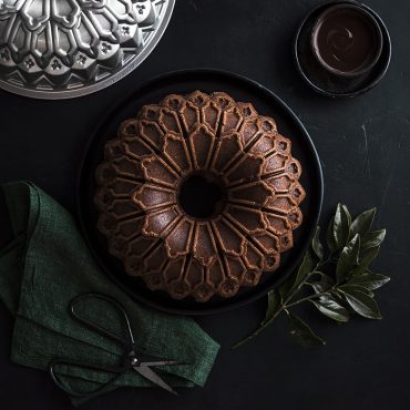 Chocolate bundt cake with decorative geometric pattern baked in Nordic Ware Stained Glass bundt pan, dark aluminum finish
