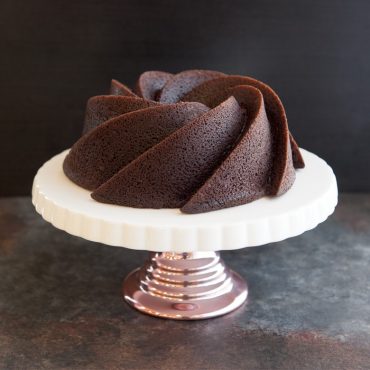 Dark chocolate bundt cake with Heritage pan's distinctive swirled fluted design on white pedestal stand