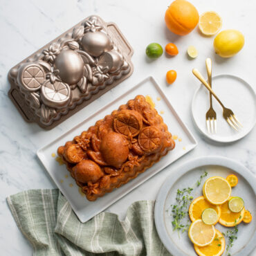 citrus blossom loaf cake on a white plate with whole and sliced lemons