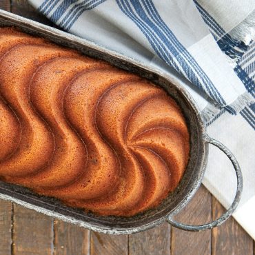 Golden vanilla loaf cake in Nordic Ware Heritage aluminum pan with elegant swirled design pattern
