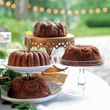 Four chocolate bundt cakes with different decorative patterns baked in Nordic Ware Quartet pan, displayed on cake stands
