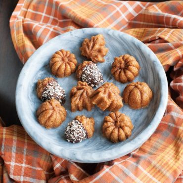Nordic Ware aluminum cakelet pan with baked pumpkin-shaped cakes, some dusted with powdered sugar