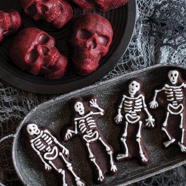 Chocolate skeleton cakelets with white frosting details and red velvet skull cakes from Nordic Ware pan