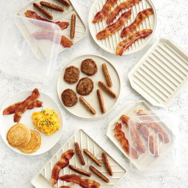 Nordic Ware aluminum bacon trays with slanted ridges, containing cooked bacon strips and sausage links