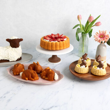 Charlotte cake with decorative fluted design alongside Easter-themed baked goods including chocolate bunny shortcakes and lamb cake