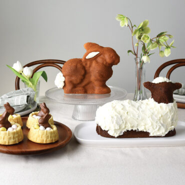 Easter display featuring Nordic Ware 3D bunny cake on stand, lamb cake, and shortcake baskets with chocolate decorations