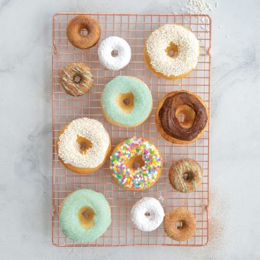 Assorted glazed and cake donuts, both full-size and mini varieties, arranged on wire cooling rack