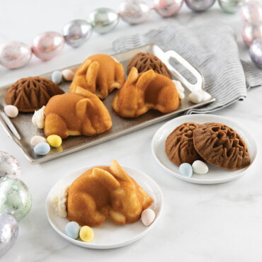 Golden baked bunny and egg-shaped cakelets arranged on white surface, showing detailed molded features