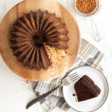Chocolate bundt cake in Nordic Ware Brilliance pan with decorative ridged design, slice on plate with fork