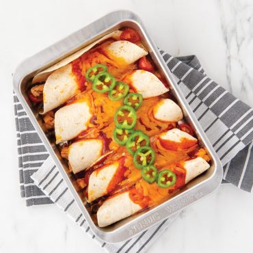 Baked enchiladas with melted cheese in Nordic Ware aluminum rectangular baking dish, natural finish