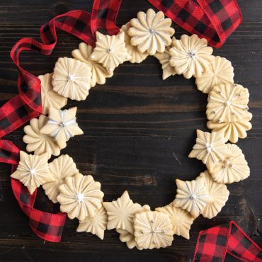 Golden stamped cookies arranged in wreath formation with red ribbon, made using Nordic Ware Pretty Pleated cookie stamps