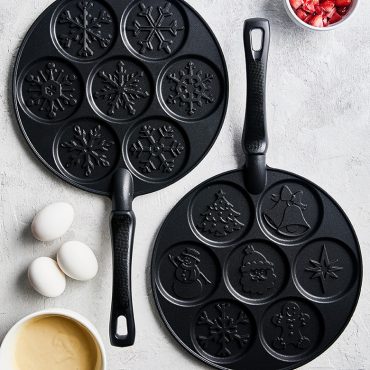 Nordic Ware aluminum pancake pan with six snowflake-shaped wells, natural silver finish on white surface