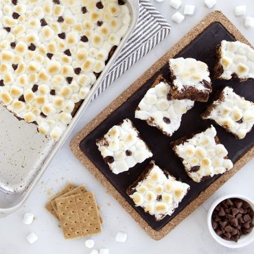 Golden s'mores bars cut into squares on white platter, baked in Nordic Ware aluminum rectangular baking pan