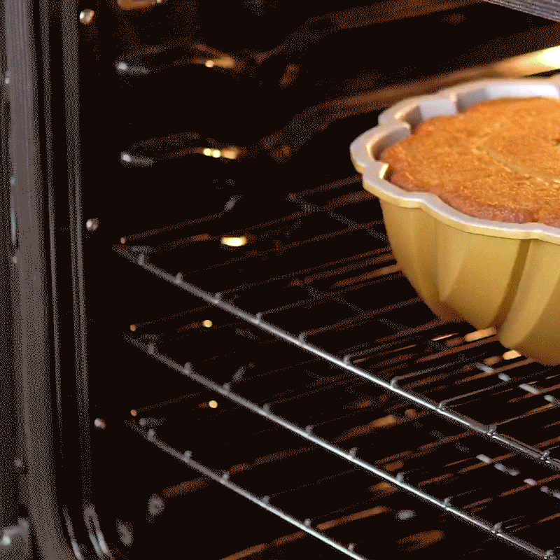 Golden bundt cake being removed from Nordic Ware braided bundt pan using protective hot pads