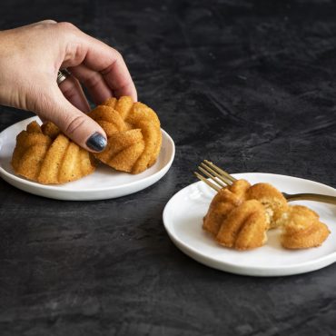 Six golden mini bundt cakes with braided rope pattern baked in Nordic Ware aluminum anniversary pan
