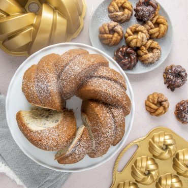 Six golden braided bundt cakes displayed with Nordic Ware aluminum mini bundt pans in background