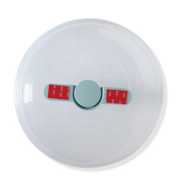 Nordic Ware Up & Away spatter cover with red protective tape strip, overhead view showing compact design