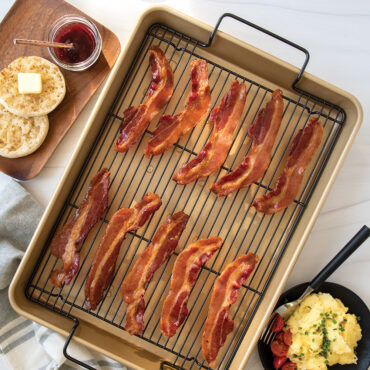 Nordic Ware nonstick high-sided baking tray with crispy golden bacon strips arranged in rows