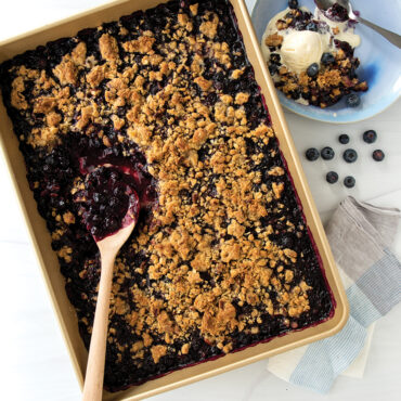 Nordic Ware nonstick high-sided rectangular baking tray with golden baked fruit cobbler, dark coating