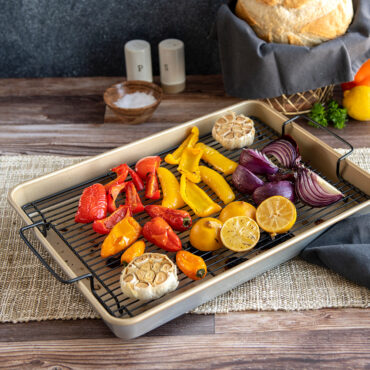 Nordic Ware nonstick high-sided baking tray with golden roasted vegetables including broccoli and carrots