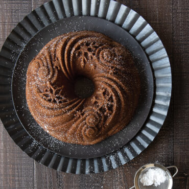 Golden bundt cake in Nordic Ware Let It Snow aluminum pan, featuring snowflake and winter tree pattern details