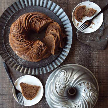 Nordic Ware Let It Snow bundt pan with baked golden cake featuring snowflake pattern, partially sliced