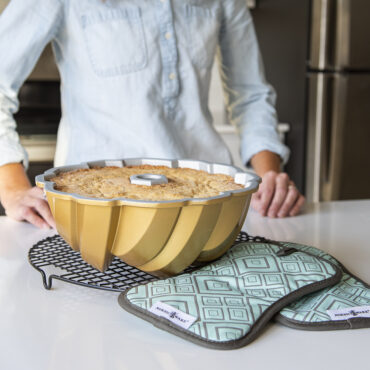 Nordic Ware silicone bundt-shaped hot pads in front of golden baked bundt cake with fluted design