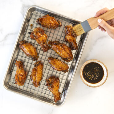 Nordic Ware aluminum quarter sheet pan with black nonstick cooling grid, displaying golden cooked chicken wings