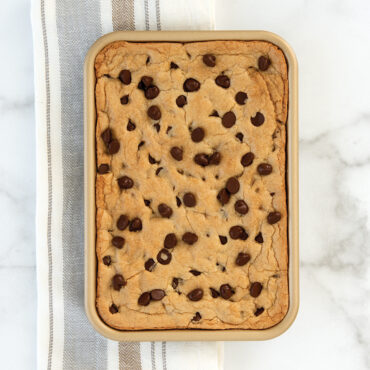 Nordic Ware aluminum eighth sheet baking pan with golden baked cookies, natural finish with raised edges