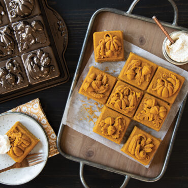 Nordic Ware aluminum Seasonal Squares pan with 12 baked golden square cakelets featuring autumn leaf designs