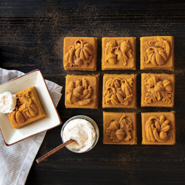Nordic Ware Seasonal Squares aluminum baking pan with six baked square cakelets topped with white cream