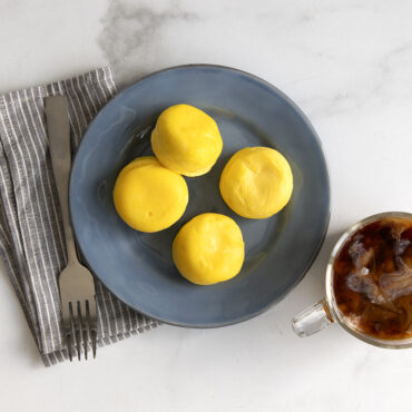 Fluffy golden egg bites arranged on white plate next to coffee cup, made with Nordic Ware egg bites pan