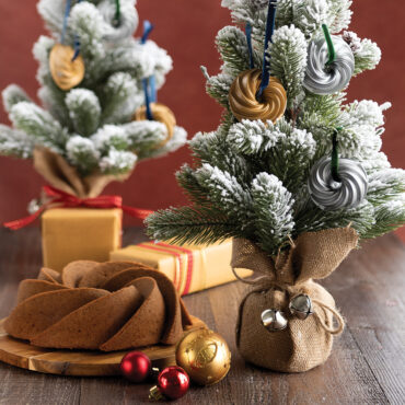 Two gold-colored Nordic Ware Heritage Bundt pan ornaments with detailed fluted ridges, miniature collectible versions