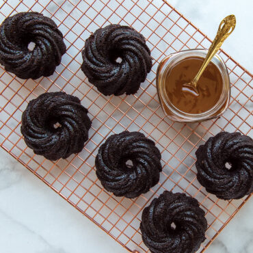 Six chocolate swirl bundtlettes cooling on copper wire rack, showing detailed ridged pattern from Nordic Ware pan