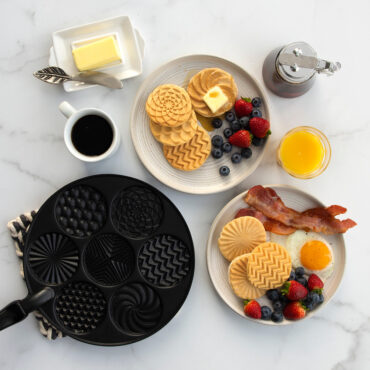 Nordic Ware aluminum pancake pan with 7 round wells, 6 golden pancakes with geometric patterns cooked inside